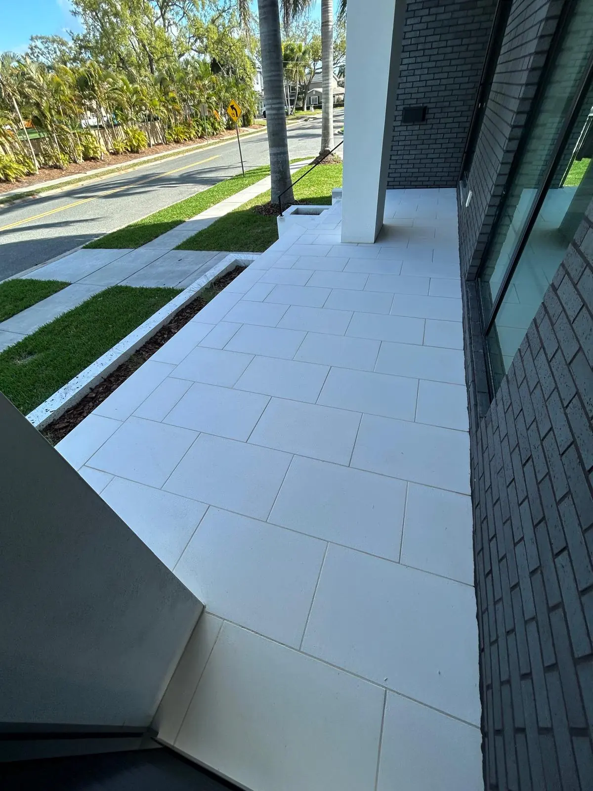 Front entry walkway in large-format white stone running along the house toward the street
